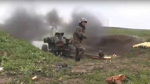 This image taken from a video released by Armenian Defense Ministry on Friday, Oct. 2, 2020 an Armenian serviceman fires a cannon towards Azerbaijan positions at the contact line of the self-proclaimed Republic of Nagorno-Karabakh, Azerbaijan.