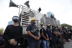 Security staff stand in front of a truck used as a stage during a rally outside the Siam Commercial Bank,a publicly-held company in which the Thai king is the biggest shareholder,Wednesday, Nov. 25, 2020, in Bangkok Thailand.