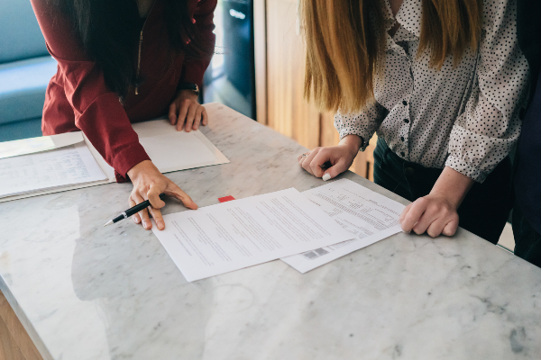 Two people's hands handling sheets of paper on a table from a birds-eye view