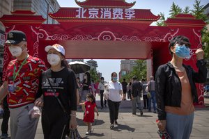 People wearing face masks to protect against the new coronavirus walk at a government event aiming to stimulate consumer demand and consumption in Beijing, Saturday, June 6, 2020