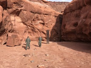 On November 18, 2020, the Utah Department of Public Safety Aero Bureau was working with the Utah Division of Wildlife Resources to conduct a count of big horn sheep in a portion of southeastern Utah. While on this mission, they spotted an unusual object and landed nearby to investigate further. The crew members (pictured) found a metal monolith installed in the ground in a remote area of red rock.