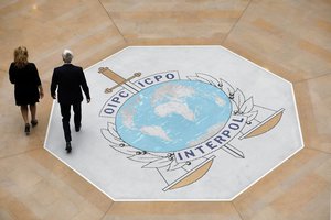 People walk on the Interpol at the international police agency logo in Lyon, central France, Thursday, Nov.8, 2018