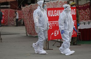 Medical staff members dressed in protective suits walk toward railway station as special train carrying passengers from New Delhi railway station arrives in Jammu, India, 14 May 2020.