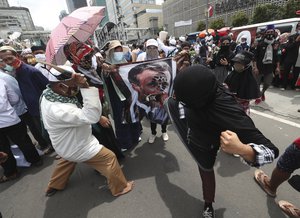 An Indonesian Muslim protester kicks a defaced poster of French President Emmanuel Macron during an anti-France rally outside the French embassy in Jakarta, Indonesia, Monday, Nov. 2, 2020.