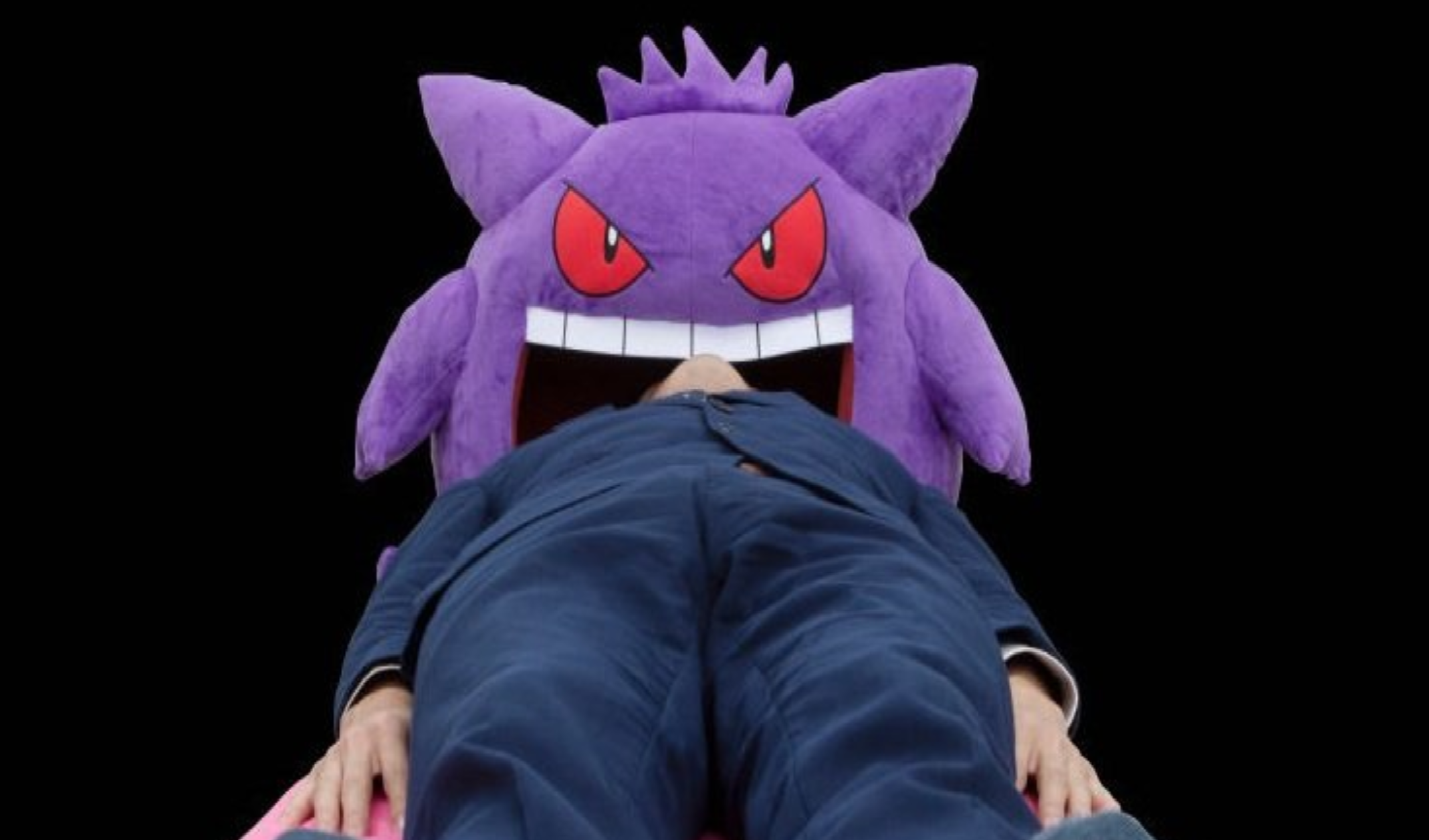 A person with their head inside a Gengar cushion