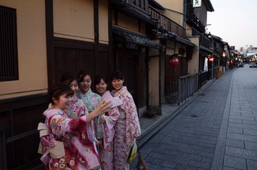 A group of Japanese women wearing kimono takes a selfie in the Gion district of Kyoto, Japan. Japanese tourism industry ...