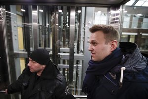 Russian opposition figure and anti-corruption campaigner Alexei Navalny, right, is escorted by bailiffs in a business center outside his office in Moscow, Russia