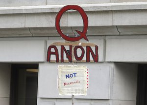 In this May 14, 2020, photo, a person carries a sign supporting QAnon at a protest rally in Olympia, Wash., against Gov. Jay Inslee and Washington state stay-at-home orders made in efforts to prevent the spread of the coronavirus.