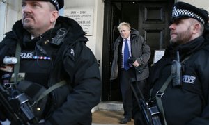 The Mayor of London Boris Johnson leaves past two armed police officers after visiting the French Embassy in London, Thursday, Jan. 8, 2015.