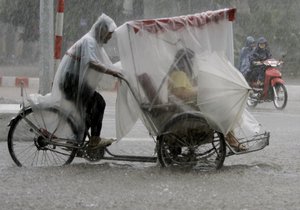 A tricycle rider transports his passenger on a flooded street caused by heavy rain in Hanoi, Vietnam Tuesday, Sapt. 5, 2006.