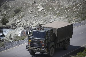 An Indian army soldier keeps guard on top of his vehicle as their convoy moves on the Srinagar- Ladakh highway at Gagangeer, northeast of Srinagar, Indian-controlled Kashmir, Tuesday, Sept. 1, 2020.