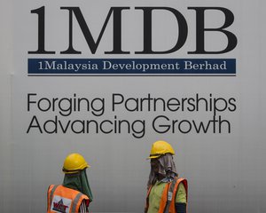 FILE - In this May 14, 2015 file photo, construction workers chat in front of a billboard for state investment fund 1 Malaysia Development Berhad (1MDB) at the fund's flagship Tun Razak Exchange development in Kuala Lumpur, Malaysia.