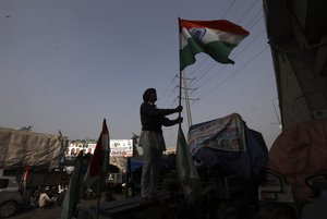 An Indian farmer erects the Indian flag after arriving at the Delhi-Uttar Pradesh border for Tuesday's tractor rally in New Delhi, India, Monday, Jan. 25, 2021