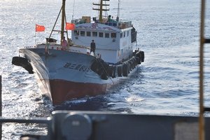 In this photo released by the U.S. Navy, crewmember on a Chinese trawler uses a grapple hook in an apparent attempt to snag the towed acoustic array Sunday, March 8, 2009 of the military Sealift Command ocean surveillance ship USNS Impeccable in the South China Sea on Sunday, March 8, 2009.