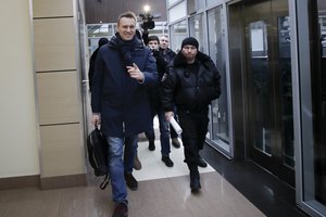 Russian opposition figure and anti-corruption campaigner Alexei Navalny, left, is escorted by bailiffs in a business center outside his office in Moscow, Russia on Tuesday, Jan. 31, 2017