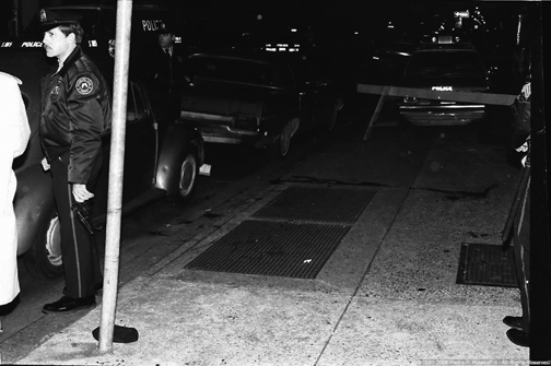 In this photo taken by freelance photographer Pedro Polakoff immediately after Officer Daniel Faulkner and Mumia Abu-Jamal were shot but suppressed by the DA and never made public until May 2006, Officer James Forbes holds both Abu-Jamal’s and Faulkner’s guns in his bare hand, touching the metal parts. This contradicts his later court testimony that he had preserved the ballistics evidence by not touching the metal parts. This is the photo that had never been published in the U.S. until it appeared on the front page of the SF Bay View on Oct. 24, 2007. – Photo: © Pedro P. Polakoff III