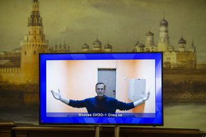 Russian opposition leader Alexei Navalny appears on a TV screen during a live session with the court during a hearing of his appeal in a court in Moscow, Russia, Thursday, Jan. 28, 2021, with the wall with the image of the Moscow Kremlin in the background.