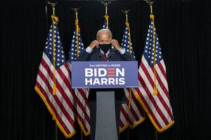 Democratic presidential candidate former Vice President Joe Biden removes his face mask as he arrives to speak at the Hotel DuPont in Wilmington, Del., Thursday, Aug. 13, 2020.