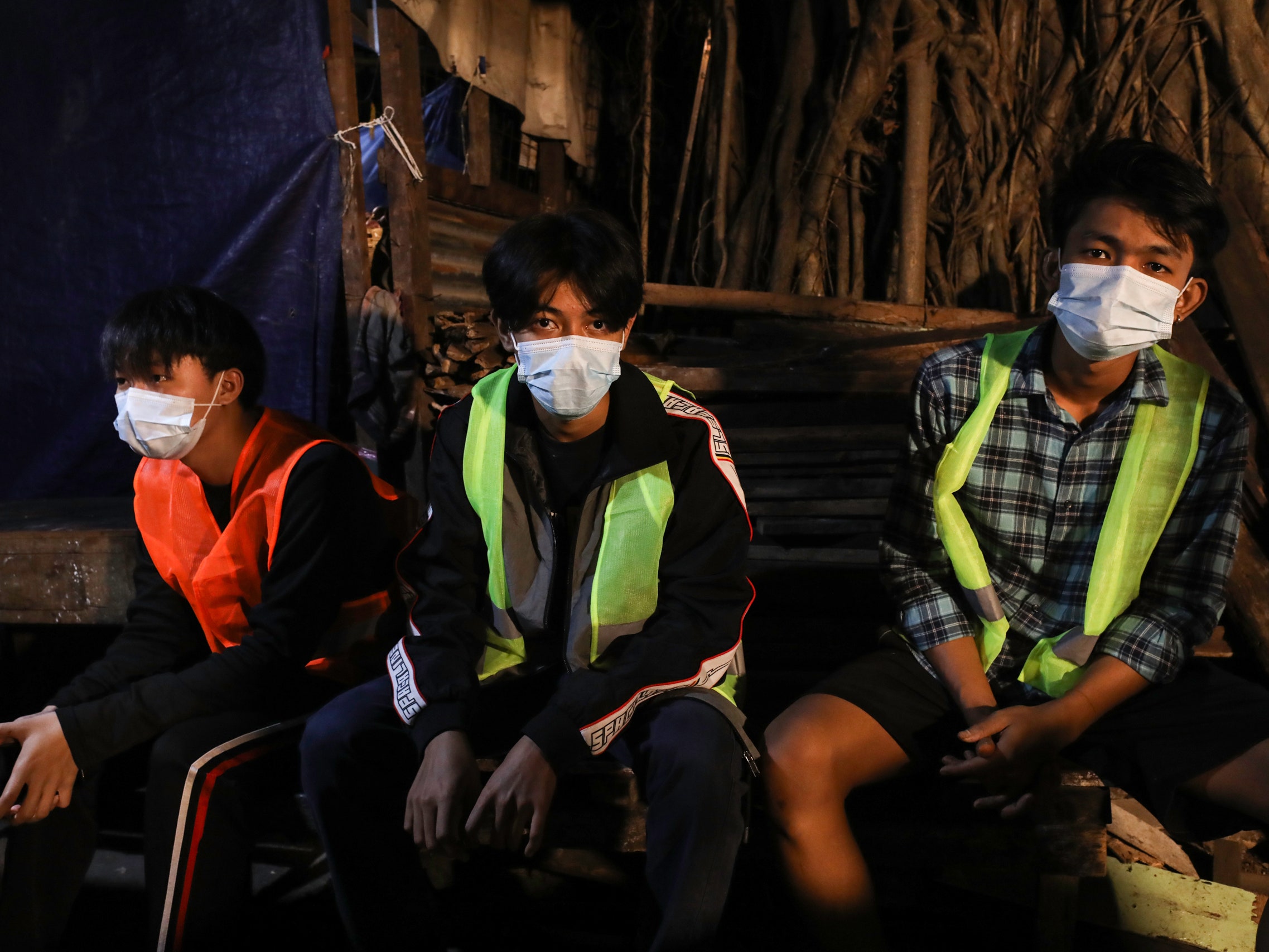 Three young people sit in reflective yellow jackets.