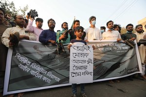 A boy joins adults during a demonstration against the death in prison of a writer who was arrested on charges of violating the sweeping digital security, in Dhaka, Bangladesh, Friday, Feb. 26, 2021.