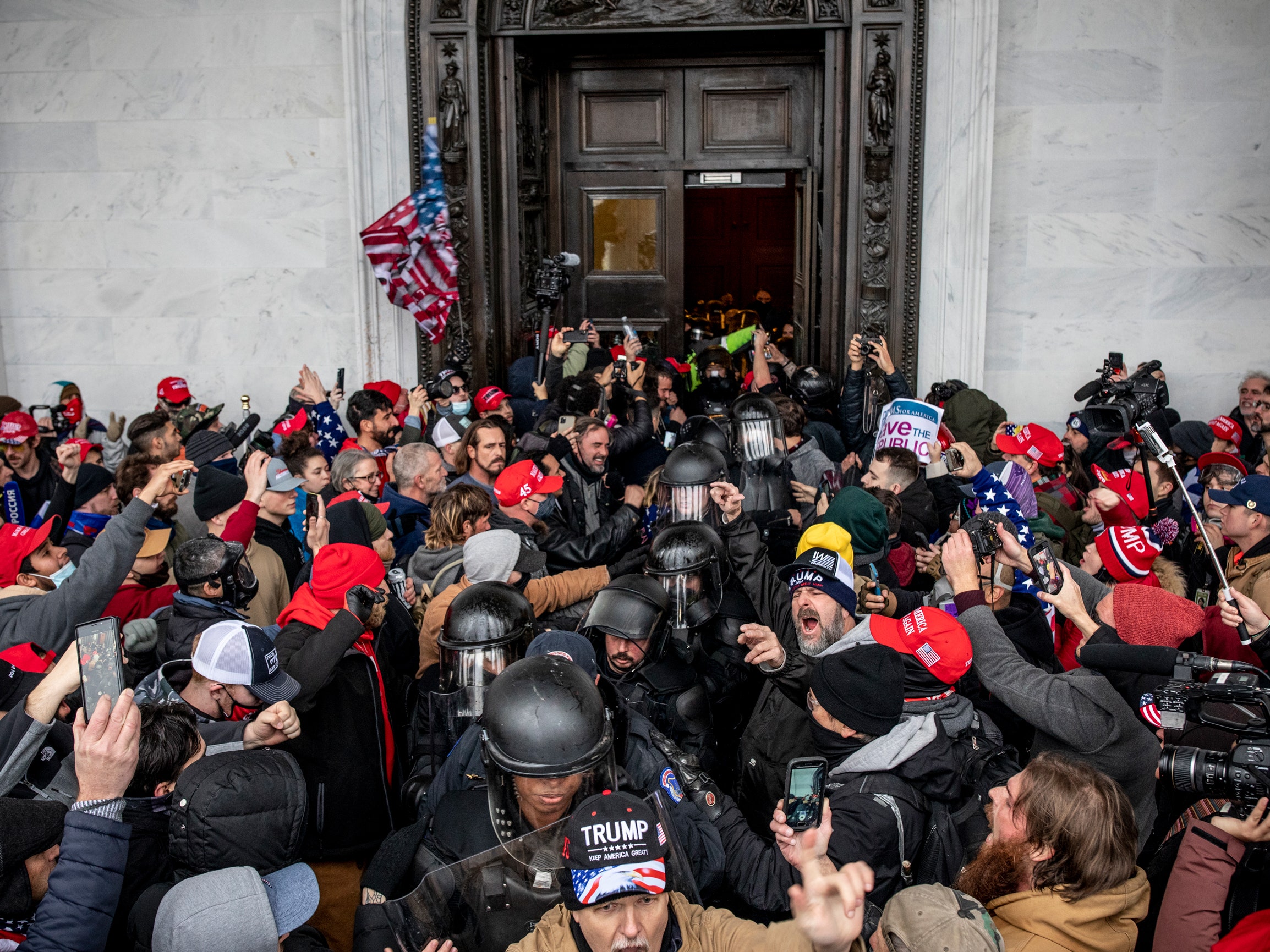 Protestors yelling as a line of Capitol Police officers walk through the crowd