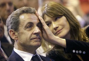 In this Thursday, Oct. 27, 2016 file picture, Carla Bruni-Sarkozy caresses the brow of her husband, the former French President and candidate for France's conservative presidential primary, Nicolas Sarkozy, during a campaign meeting in Marseille, southern France.