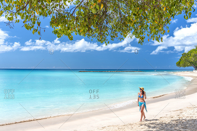 Young woman walking along Sandy Lane beach, the most pristine and prestigious coast of the island of Barbados.