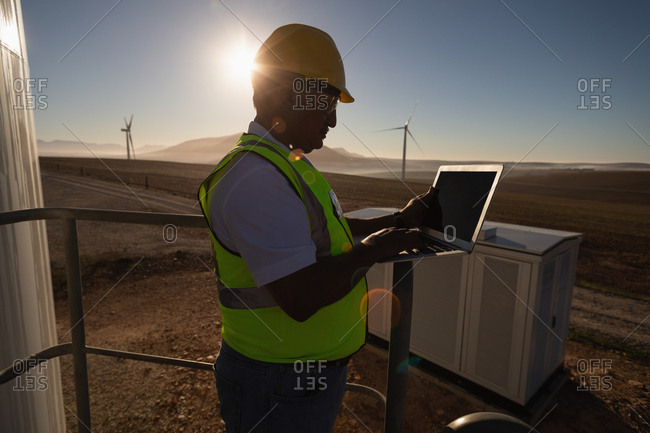 Engineer using a laptop at entrance of a wind mill at a wind farm