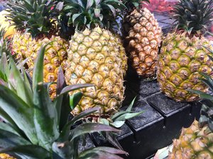 Pineapple fruits displayed on top of black boxes at a fruit shop. Taken on April 2018.