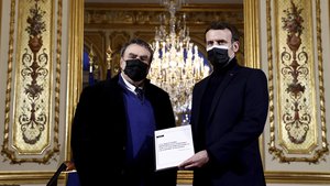 In this Jan.20, 2021 file photo Emmanuel Macron gets a report from French historian Benjamin Stora as he receives the report on the memory of the colonization and the Algerian war