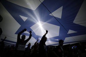 Israeli protesters carry large Israeli flag during a demonstration against Israeli Prime Minister Benjamin Netanyahu In Jerusalem, Saturday, March. 20, 2021. The weekly protests against Netanyahu’s corruption charges and his handling of the pandemic have persisted since summer, but tonight’s gathering is the last before Israel will be holding its fourth election in two years on March 23. (AP Photo/Sebastian Scheiner)