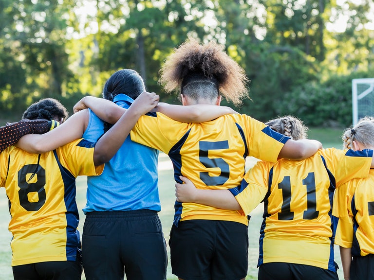 A girls' soccer team links arms. 