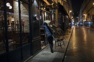 A waiter closes a bar terrace in Paris, Saturday, Oct. 17, 2020.