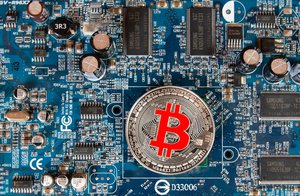 Close up photo of a silver Bitcoin on a computer mother board