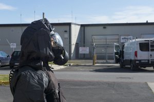 SIGONELLA, Sicily (February 20, 2018) – Master-at-Arms 2nd Class Antoinette Howell, wearing a HAZMAT suit, maintains a perimeter around the post office during a biological weapons attack drill onboard Naval Air Station (NAS) Sigonella