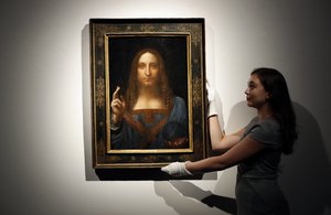 FILE - In this Oct. 24, 2017 file photo, an employee poses with Leonardo da Vinci's "Salvator Mundi" on display at Christie's auction rooms in London.