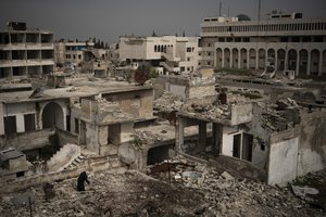 A woman stands atop a building in a neighborhood heavily damaged by airstrikes in Idlib, Syria