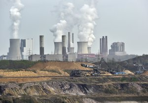 In this April 3, 2014 file photo giant machines dig for brown coal at the open-cast mining Garzweiler in front of a smoking power plant near the city of Grevenbroich in western Germany.