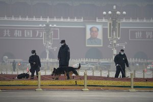 File - Police officers use sniffer dogs to check on Tiananmen Square before delegates arrive for the opening session of China's National People's Congress (NPC) at the Great Hall of the People in Beijing, Friday, March 5, 2021.