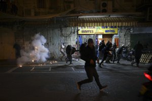 Palestinians run away as a stun grenades are fired by Israeli police during clashes at Damascus Gate just outside Jerusalem's Old City, Thursday, April. 22, 2021.