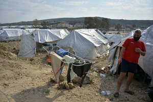 File - A migrant stands outside his tent at Karatepe refugee camp, on the northeastern Aegean island of Lesbos, Greece, Monday, March 29, 2021.