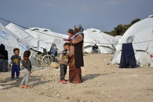 File - A woman holds a baby at Karatepe refugee camp, on the eastern Aegean island of Lesbos, Greece, Monday, March 29, 2021.