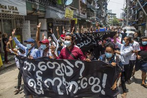 Anti-coup protesters hold a banner that reads “What are these? We are Yangon residents!” as they march during a demonstration in Yangon, Myanmar on Tuesday April 27, 2021.