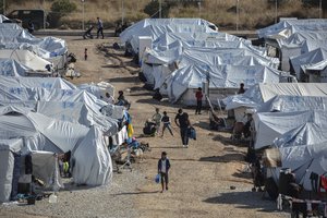 In this Wednesday, Oct. 14, 2020, file photo, migrants walk after a rainstorm at the Kara Tepe refugee camp, on the northeastern Aegean island of Lesbos, Greece.