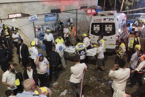 Israeli security officials and rescuers carry a body of a victim who died during a Lag Ba'Omer celebrations at Mt. Meron in northern Israel, Friday, April 30, 2021