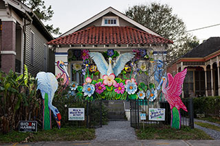 The exterior of a small single-story house is decorated with sculptural birds and flowers.