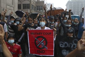 Anti-coup protester flashes the three-finger salute and chant slogan during the demonstration against the military coup in the rain at Pabedan township in Yangon, Myanmar, Friday, April 30, 2021. (AP Photo/Vincent Thian)