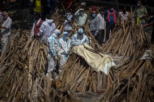 People perform rituals next to a funeral pyre for a family member who died of COVID-19 at a ground that has been converted into a crematorium for mass cremation of COVID-19 victims in New Delhi, India, Saturday, April 24, 2021.