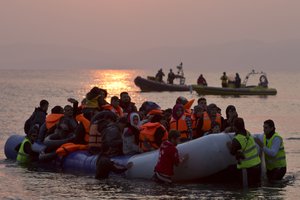 In this Sunday, March 20, 2016 file photo, volunteers help migrants and refugees on a dinghy as they arrive on the shore of the northeastern Greek island of Lesbos, after crossing the Aegean sea from Turkey.