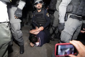 An Israeli police officer restrains a Palestinian during a protest on the eve of a court verdict that may forcibly evict Palestinian families from their homes in the Sheikh Jarrah neighborhood of Jerusalem, Wednesday, May 5, 2021